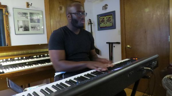 Keyboard player at a stage piano, with the Hammond organ behind him